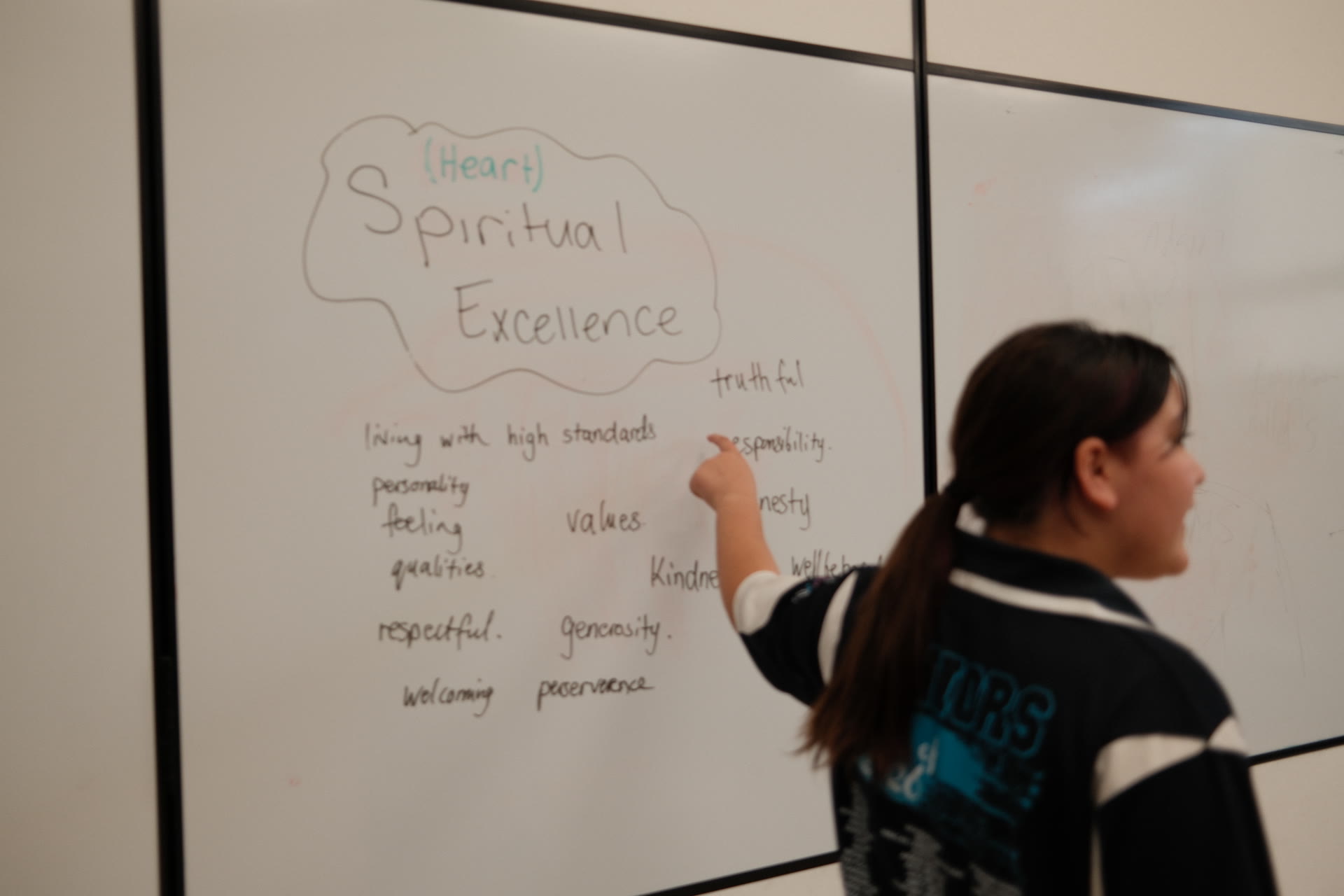A junior youth writing on the whiteboard during a session