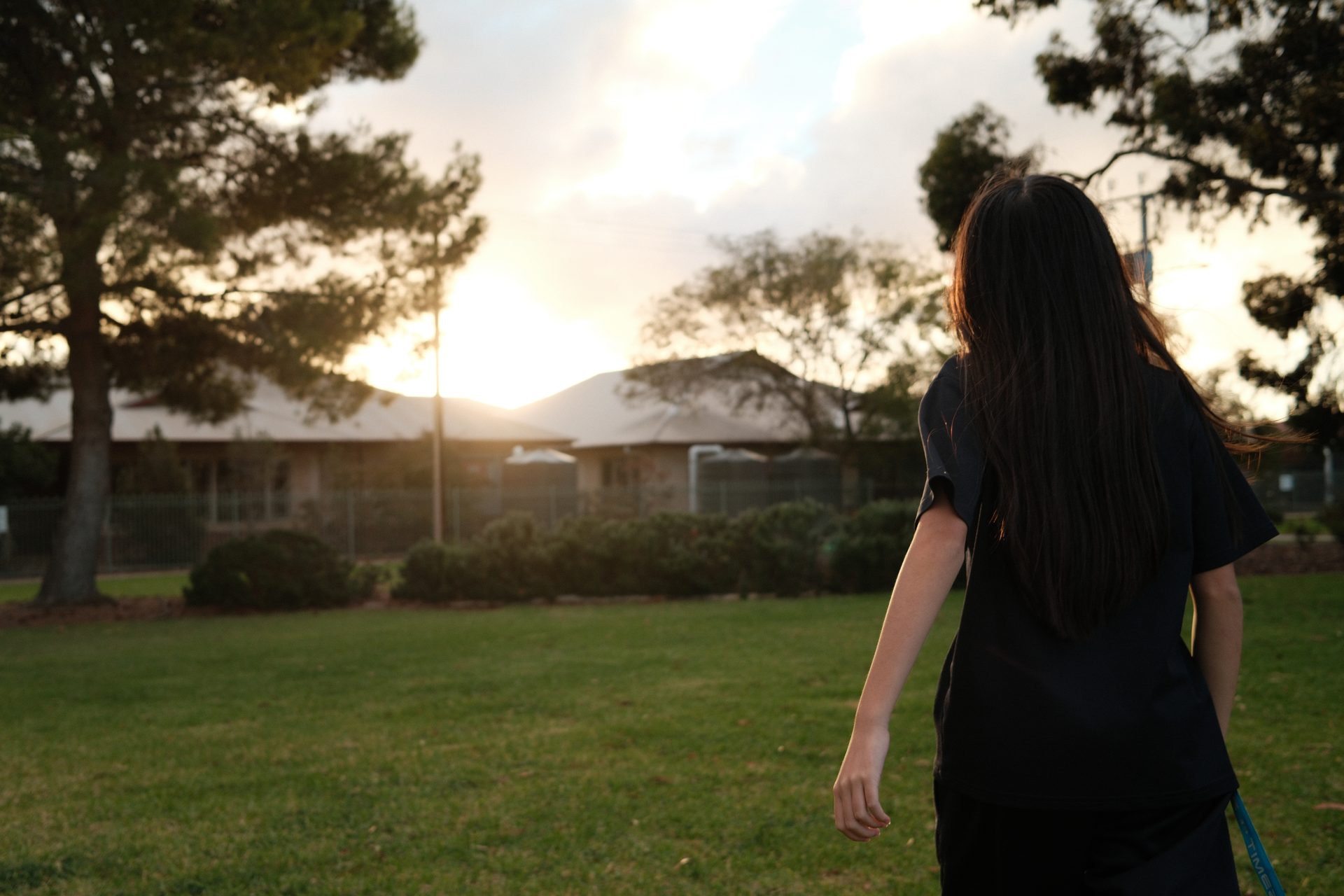 A junior youth walking across the park towards the sunset