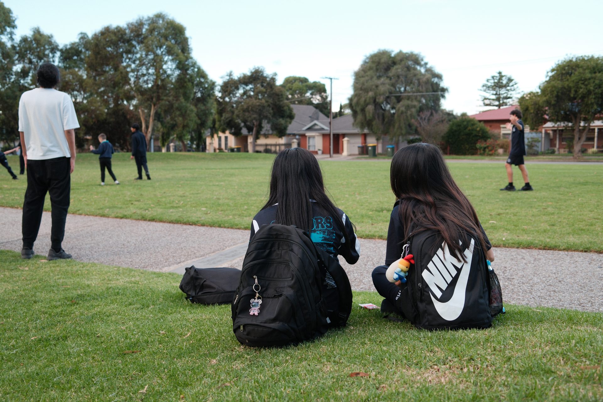 Two junior youth sitting on the grass together watching the soccer