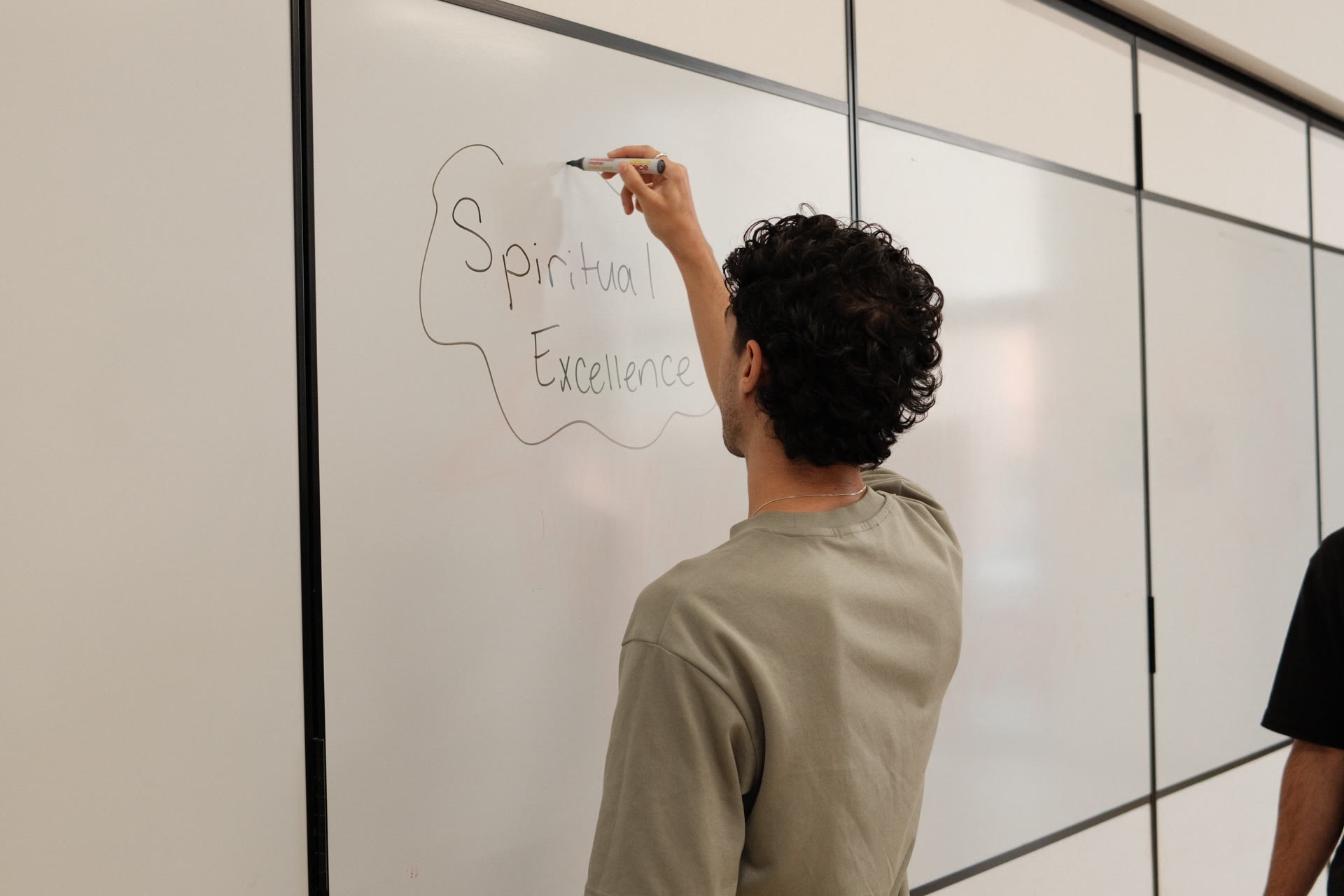 An animator writing "Spiritual Excellence" on the whiteboard